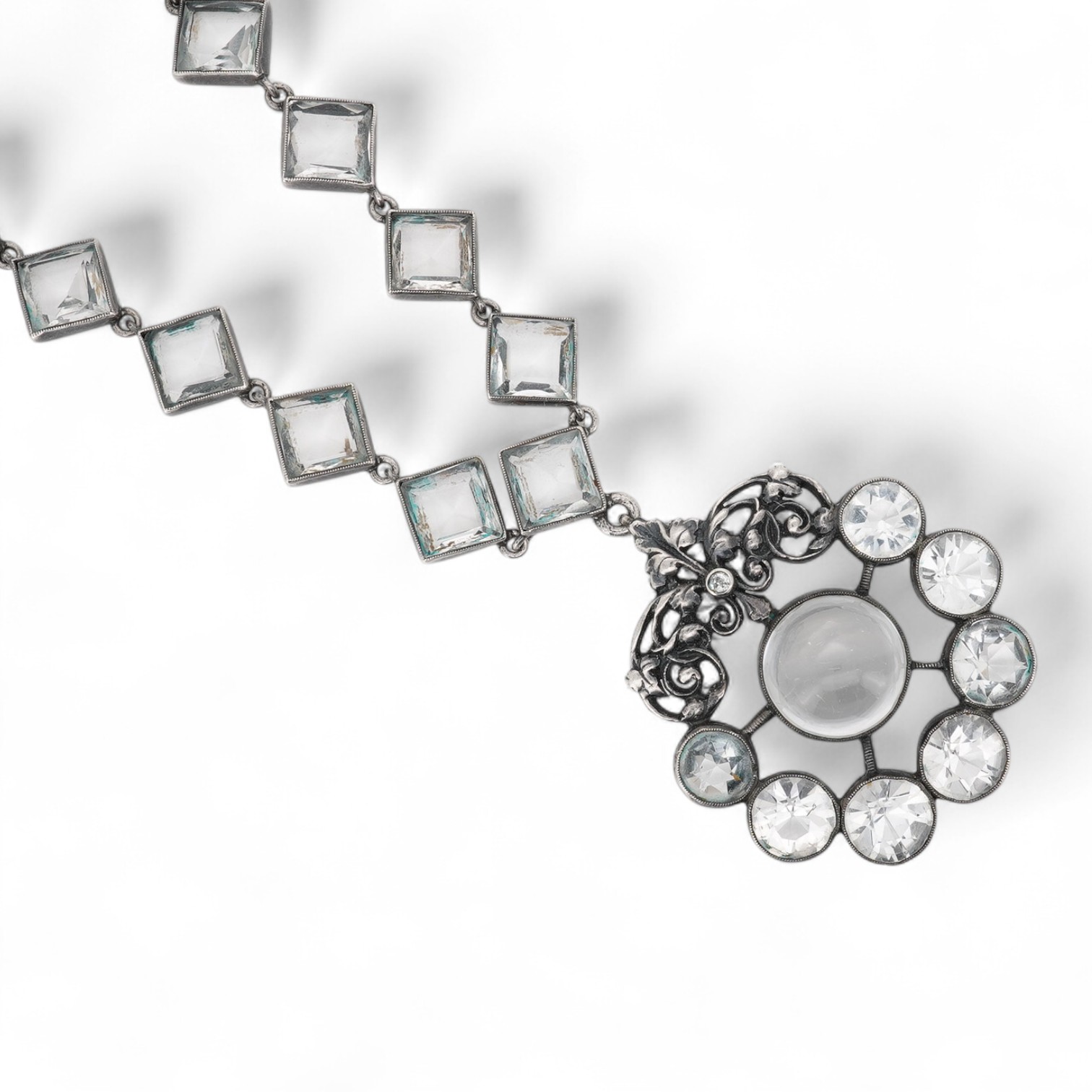 An Arts & Crafts white metal and paste cluster set circular pendant, diameter 33mm, hung from an associated white metal and quartz set necklace, 37cm.